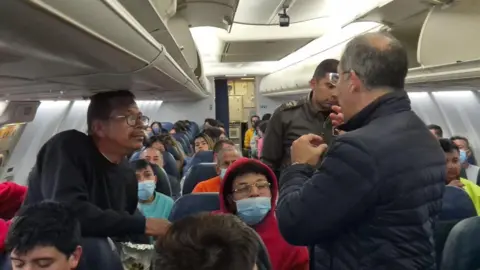 X/@Petrogustavo Gustavo Petro, mengenakan jaket biru dan menghadap jauh dari kamera, berbicara kepada para migran yang dideportasi dari AS di atas pesawat Angkatan Udara Kolombia